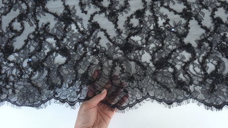 bordura festonata cu fire lungi decorative pe marginea materialului negru