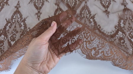 degetele ridicand o sectiune de tesatura fina si reticulara