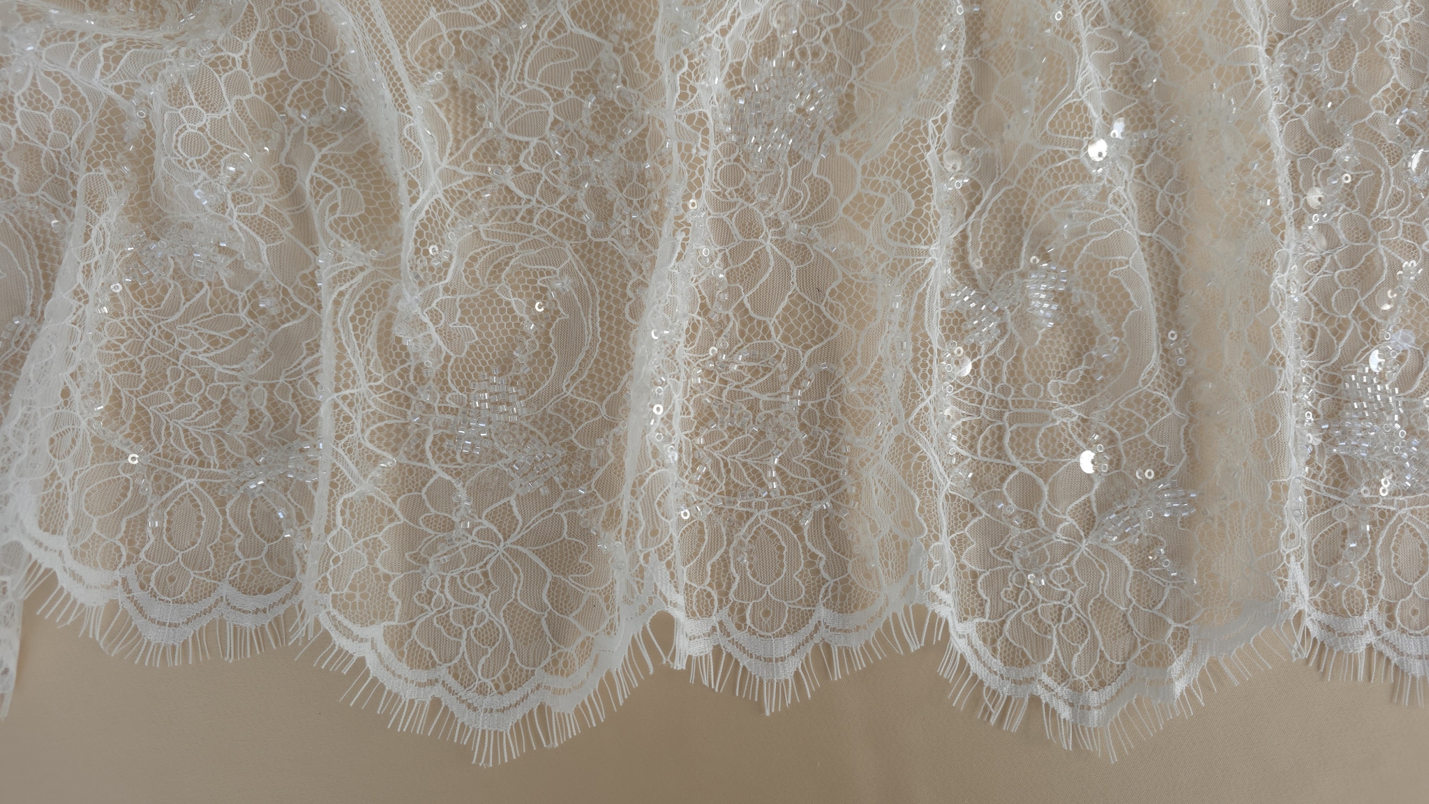 detaliu ramuri curbe brodate cu margele tubulare pe fondul transparent al tullului