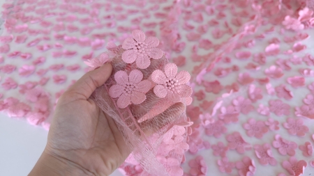 mâna care ține o porțiune de material roz cu flori reliefate