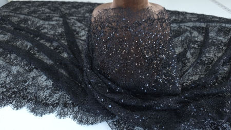 flori mici cu petale fine si ramuri subtiri brodate pe tulle negru transparent plan apropiat