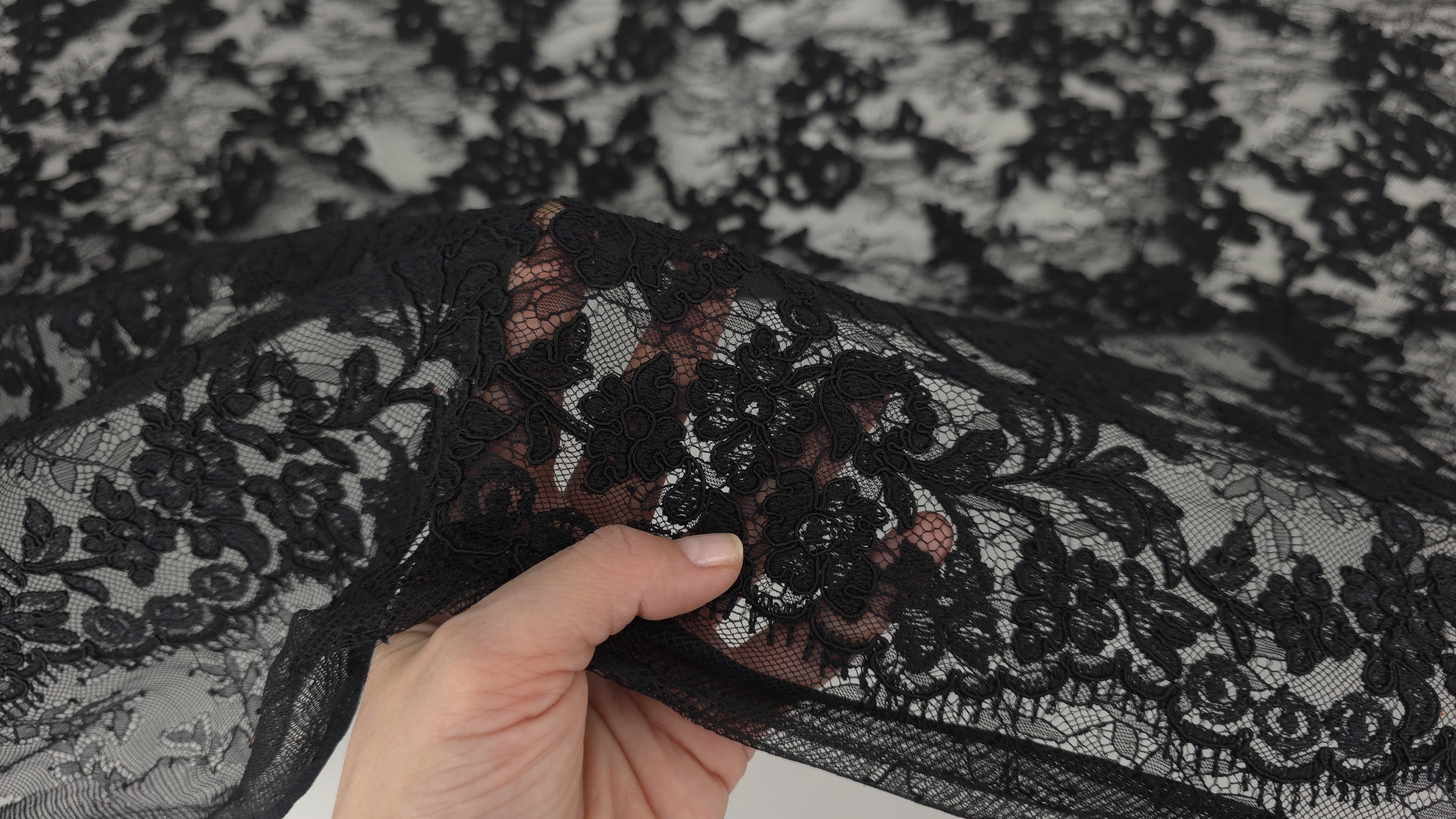 transparență excelentă a ochiurilor de tulle demonstrată prin trecerea mâinii sub material