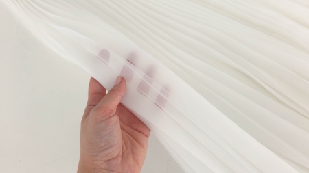 transparenta scazuta a materialului testata cu mana pe o suprafata pliata alba