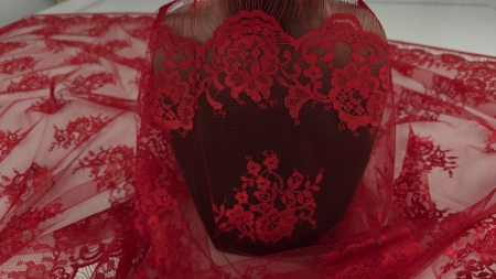 Bordura decorativă a dantelei roșu sânge drapată pe manechin cu motive florale la bază