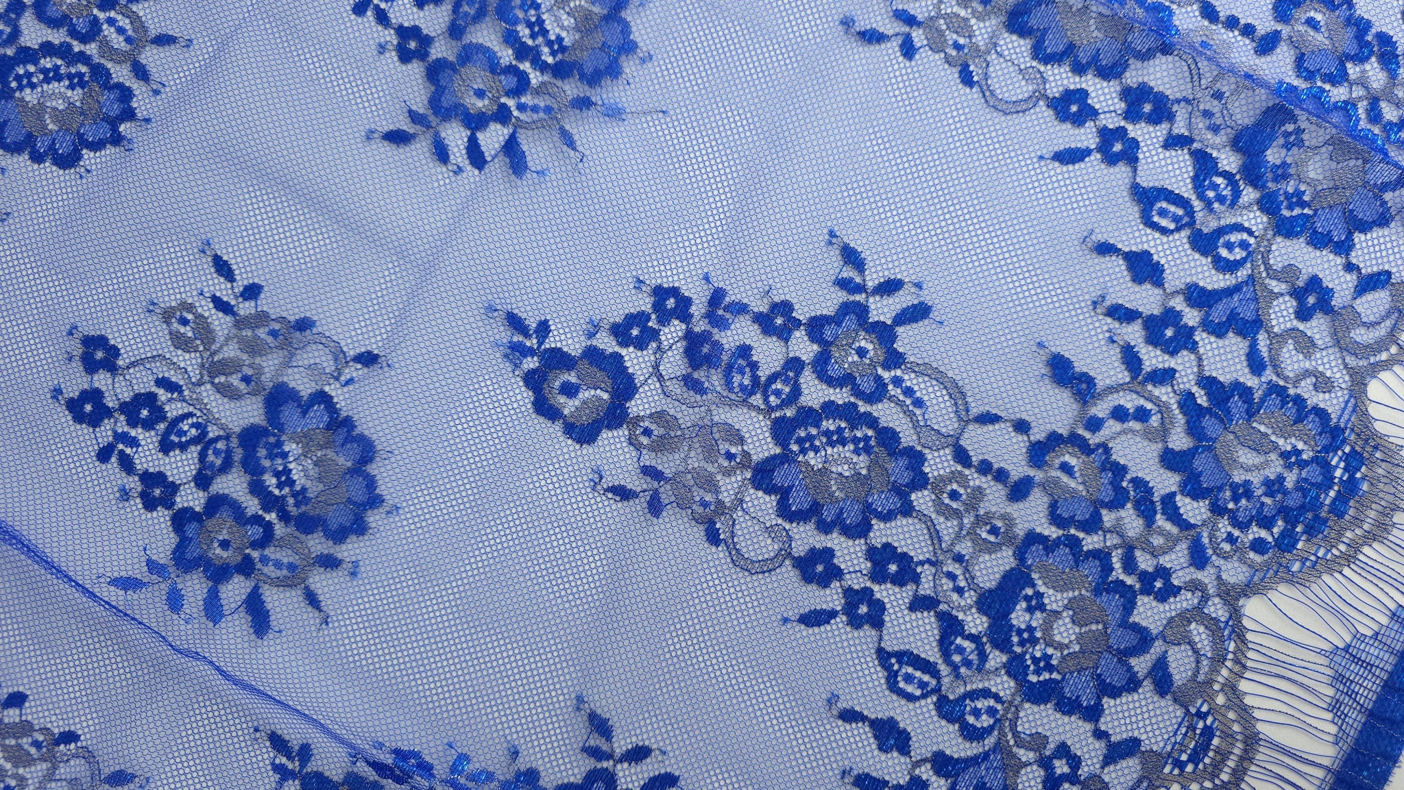 Bordură festonată cu buchete florale dense și franjuri ondulate pe tull transparent