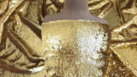 Bust de manechin acoperit cu material auriu lucios, falduri bogate în jur