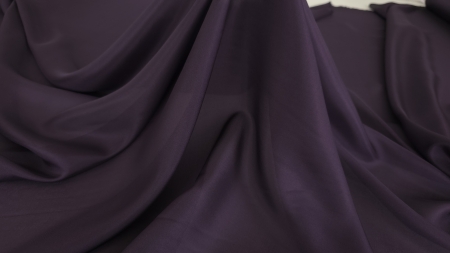 Cădere amplă și lină pe material mov prună cu falduri adânci și suprafață mată