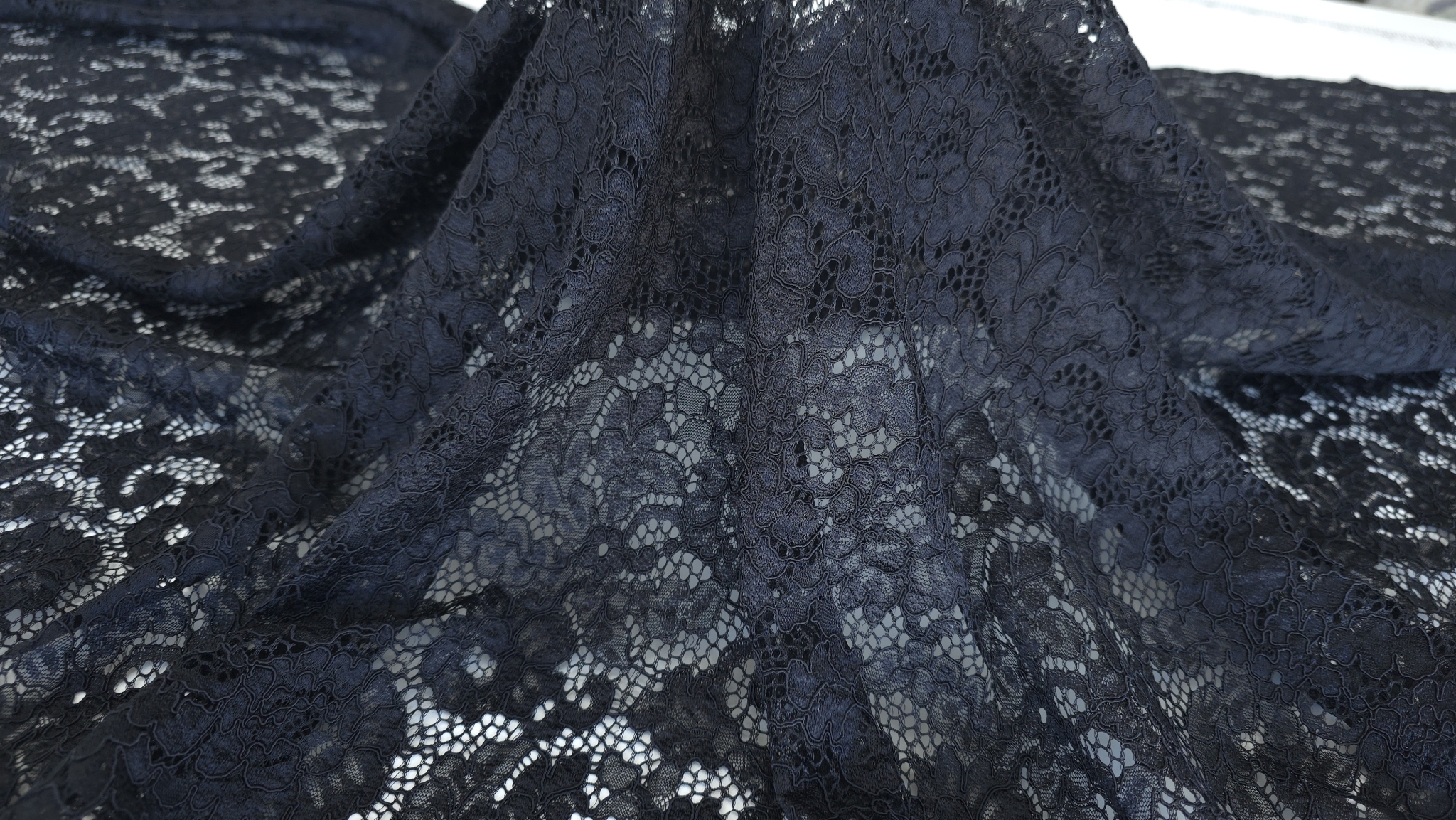 Căderea naturală a dantelei negre cu model floral ținută în mână