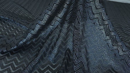 Caderea naturală a materialului negru cu falduri ample și reflexii argintii pe modelul zigzag