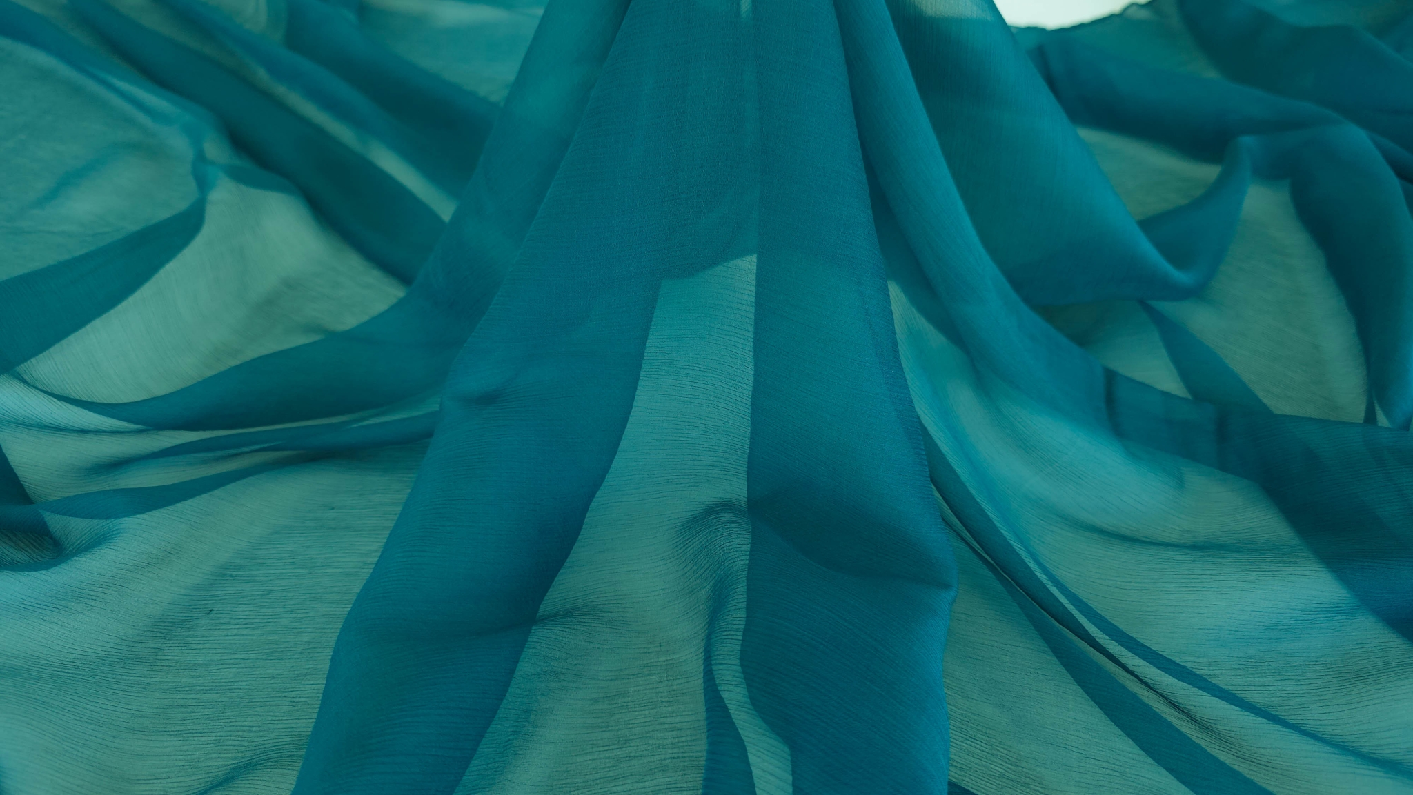 Căderea naturală a voalului albastru petrol cu falduri verticale translucide pe fundal alb