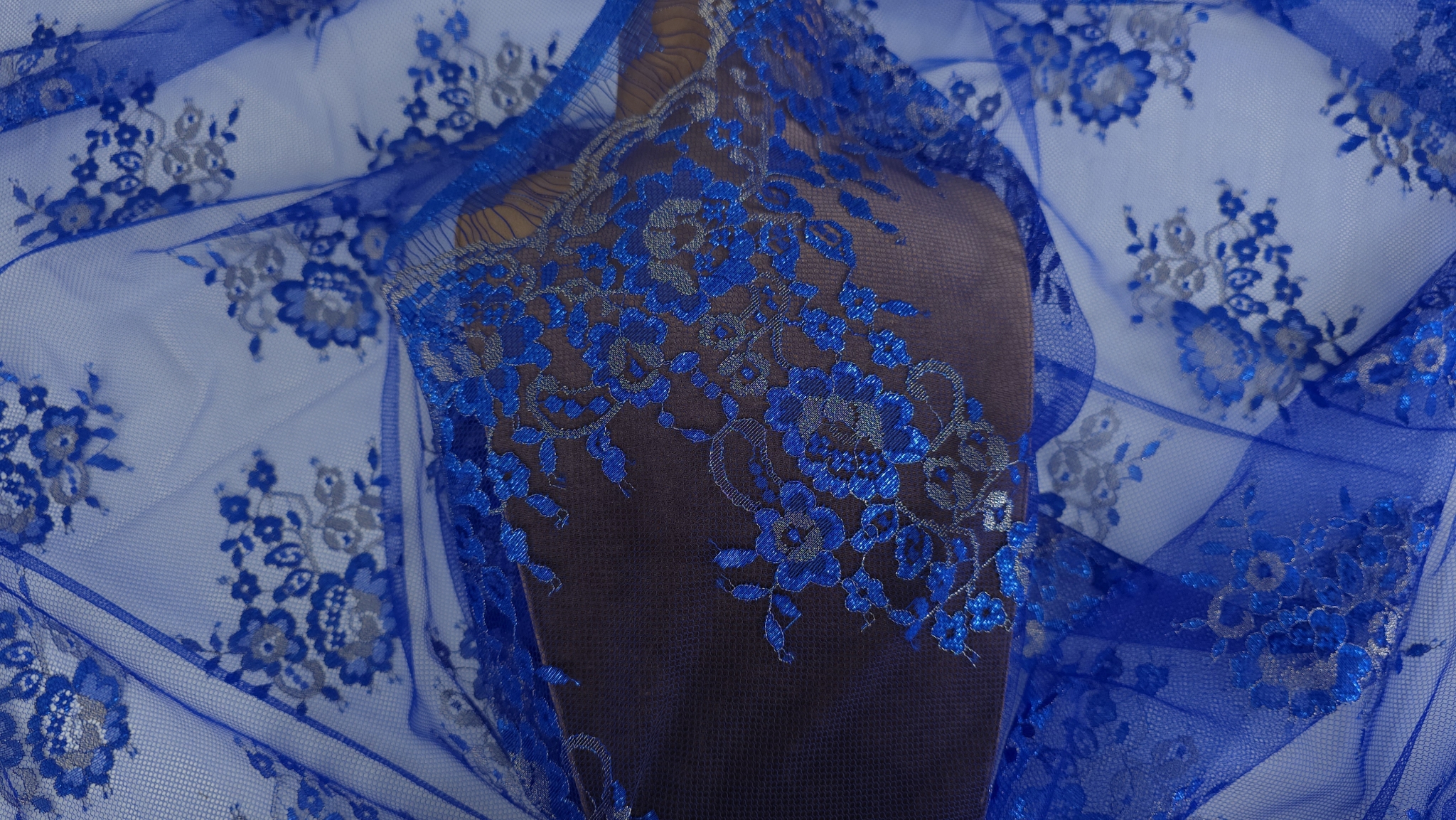 Dantela Chantilly albastru royal cu inserții argintii drapată pe manechin cu falduri ample și strălucire metalizată