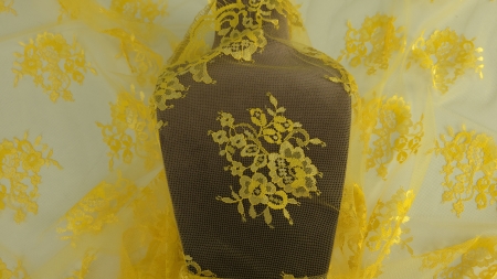 Dantela Chantilly galbenă drapată pe manechin maro cu bordura ondulată și buchete florale pe bust