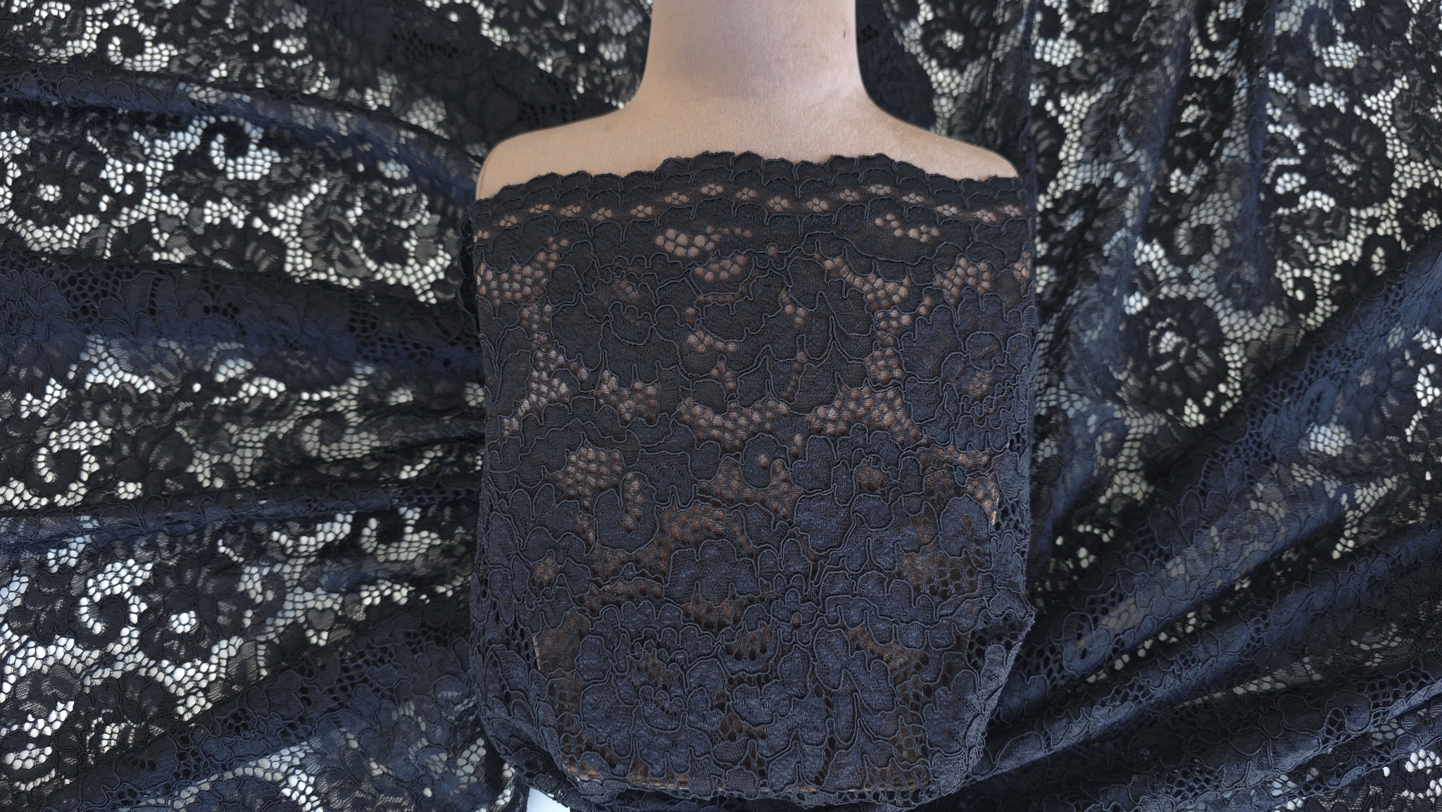 Dantelă neagră cu motive florale prezentată pe manechin, detaliu bust