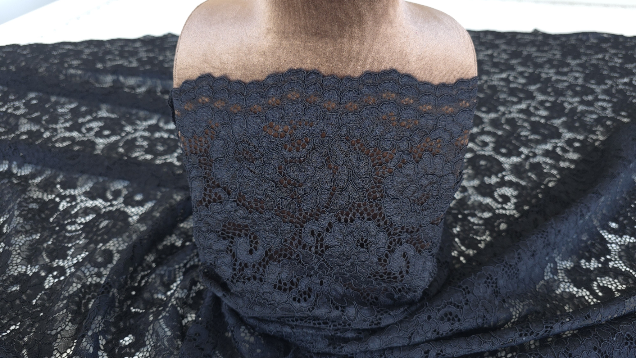 Dantelă rebordată florală neagră drapată pe manechin, vedere frontală
