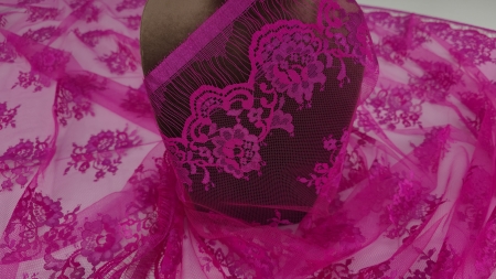 Dantela tip Chantilly fuxia drapată pe manechin maro cu bordura decorativă vizibilă la bază