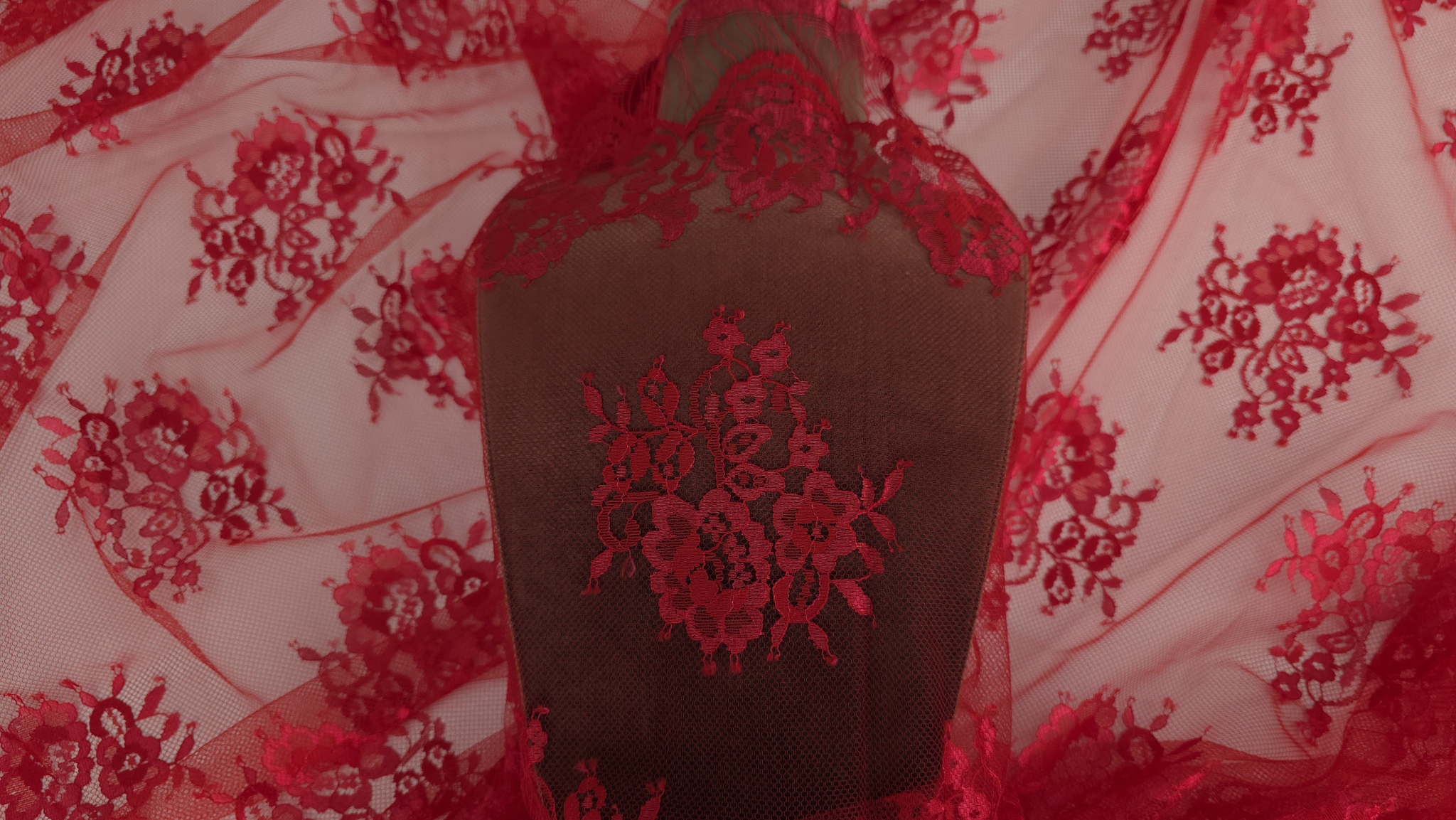 Dantela tip Chantilly rosu Ferrari desfășurată pe suprafață cu motive florale vizibile integral