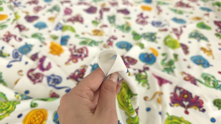 Degete care țin marginea țesăturii unde se vede firul subțire