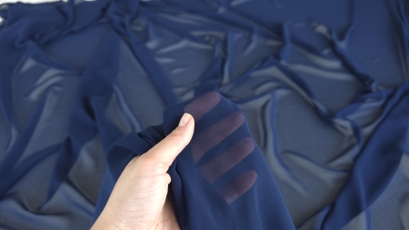 Detaliu al țesăturii strânse între degete cu transparență spre palmă