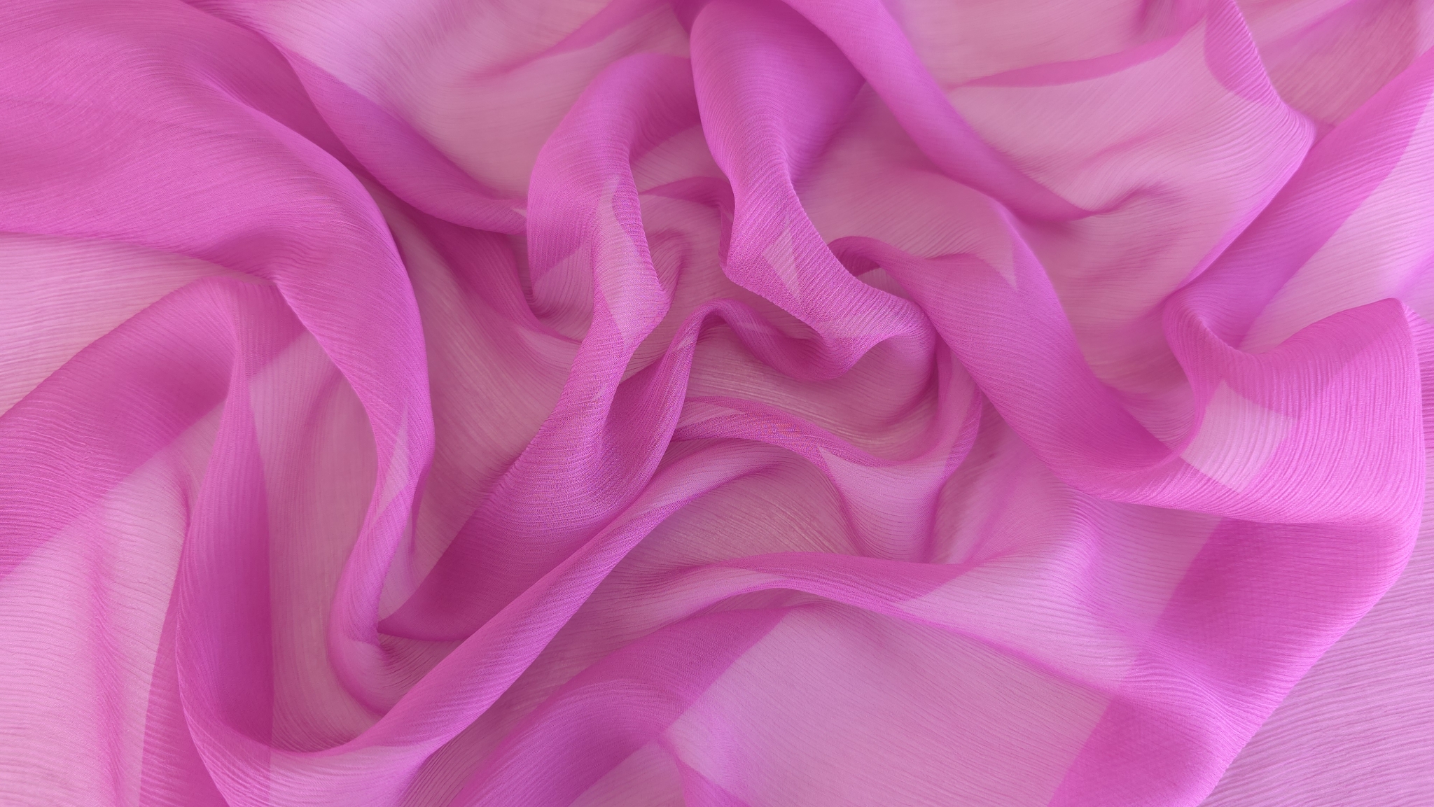 Detaliu de textură creponată fină pe suprafața voalului roz vibrant în plan apropiat