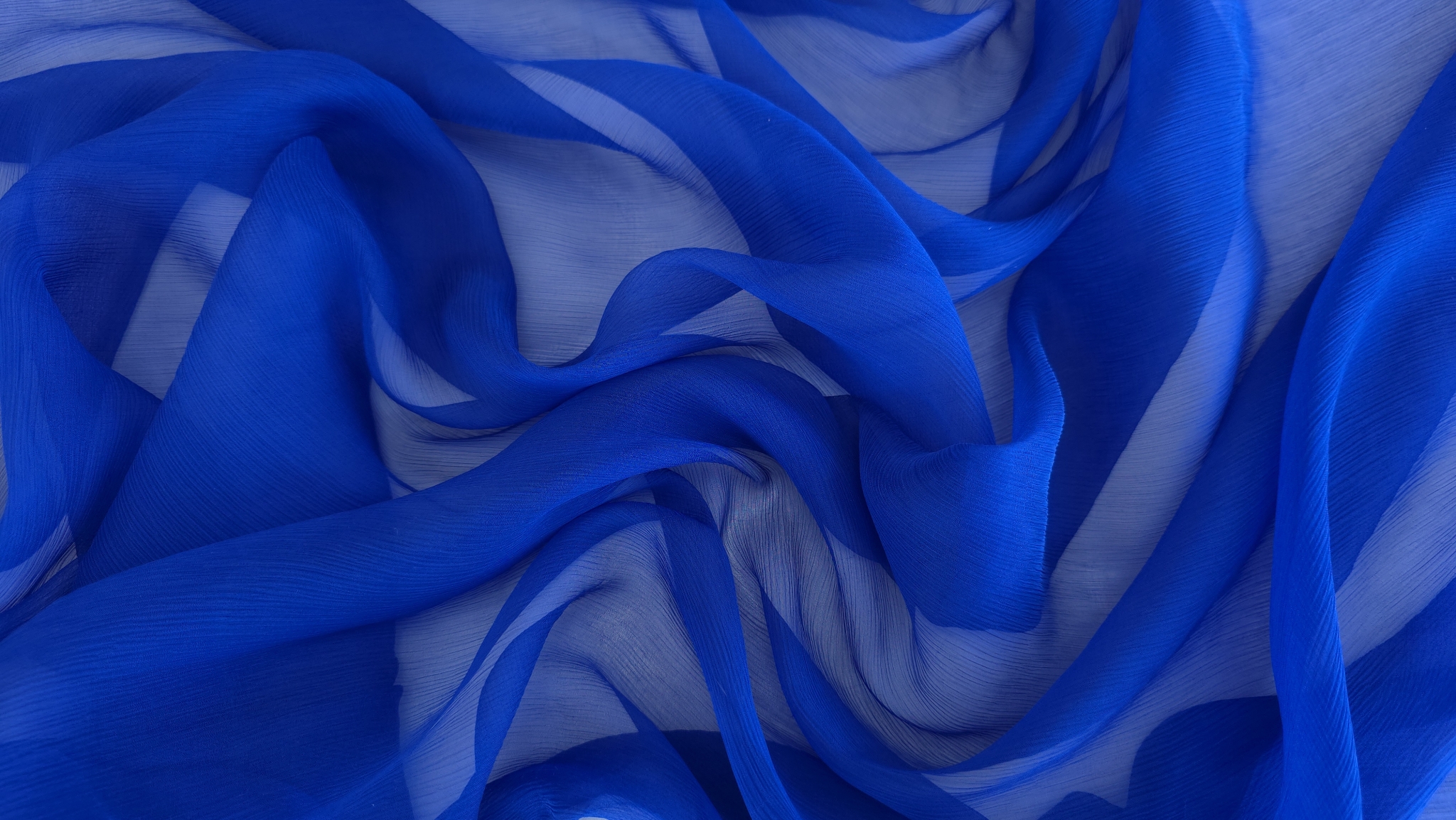 Detaliu de textură creponată fină pe voal de mătase albastru cobalt