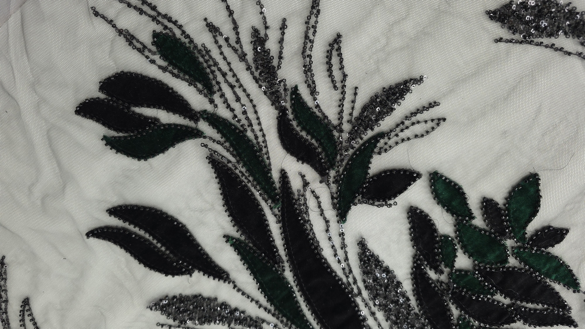 Detaliu frunze din catifea bicoloră cu margele cusute pe fond de tulle
