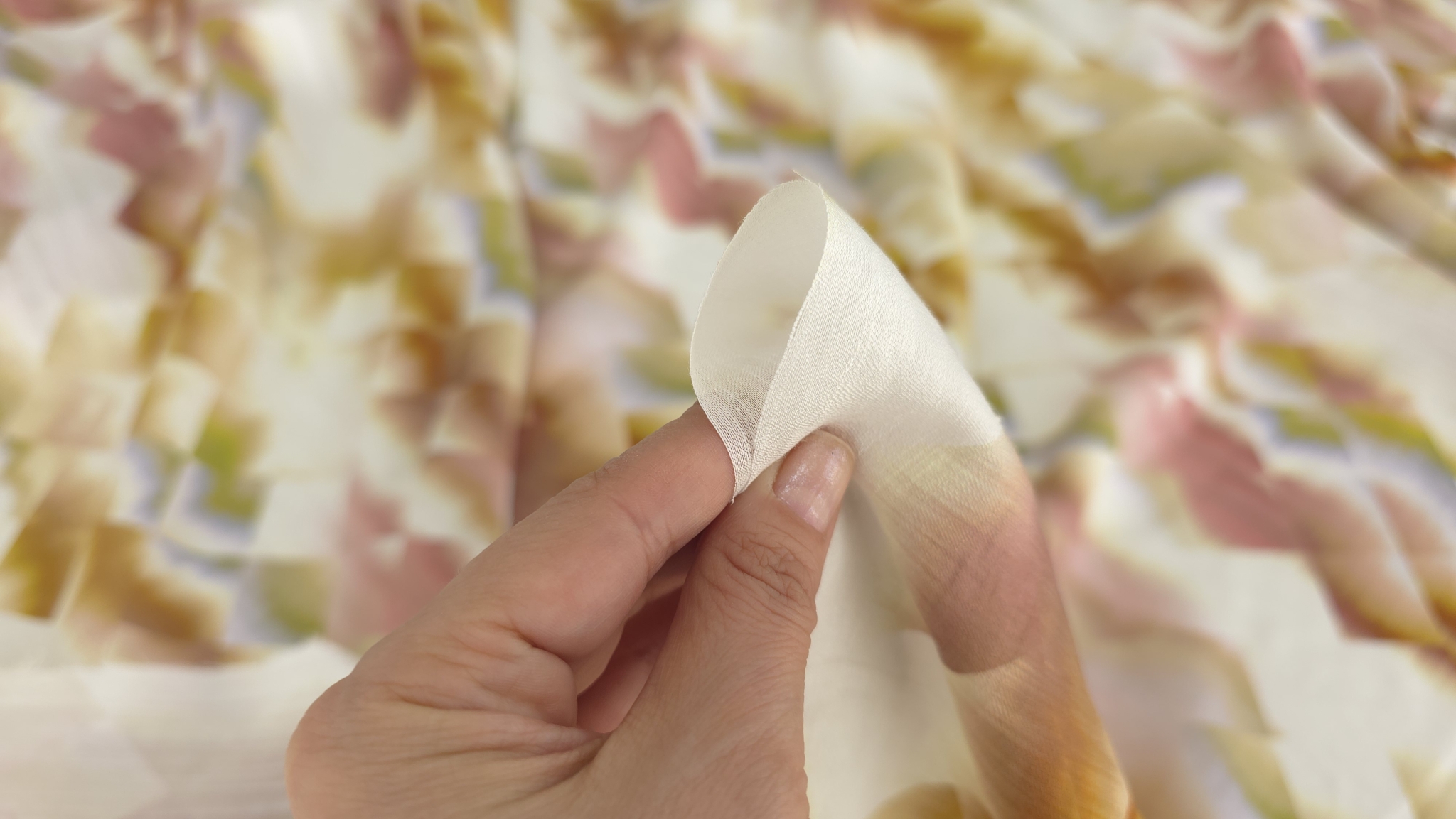 Detaliu între degete al țesăturii vascoza cu forme geometrice în tonuri de ocru și roz pal