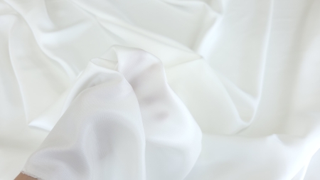 Material alb-crem ținut în mână, margine nefinisată vizibilă