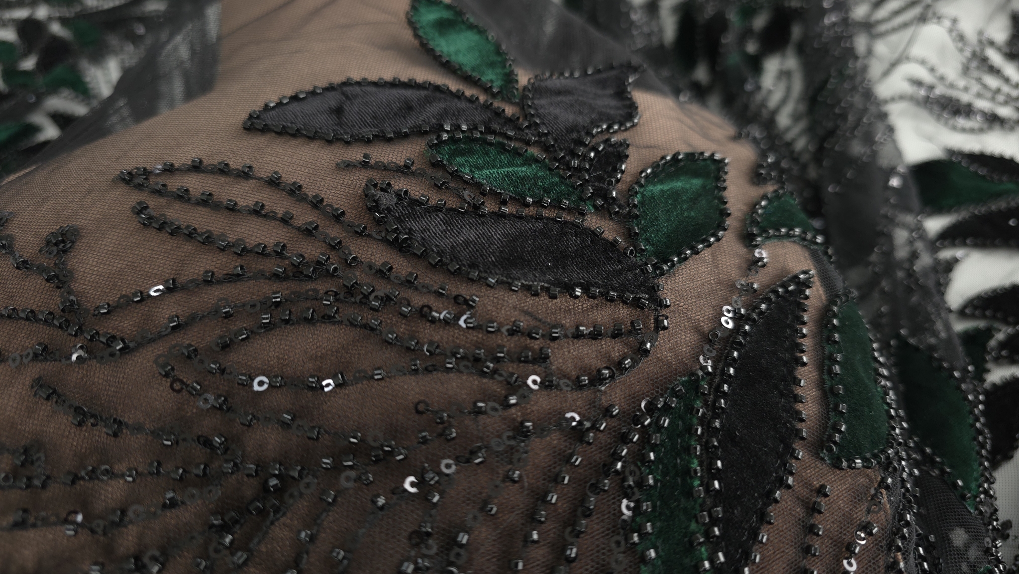 Detaliu pe manechin al frunzelor bicolore din catifea cu margele cusute pe tulle transparent