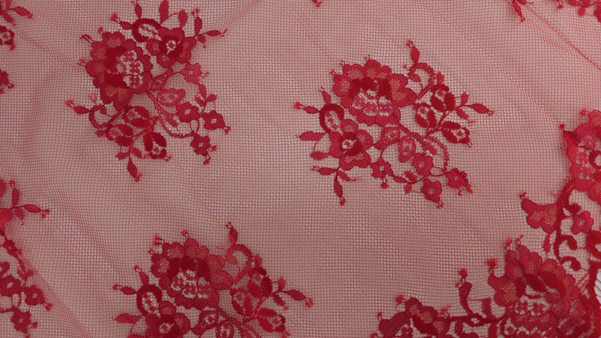 Detaliu plan apropiat al accentelor metalizate pe dantela Chantilly roșu Ferrari