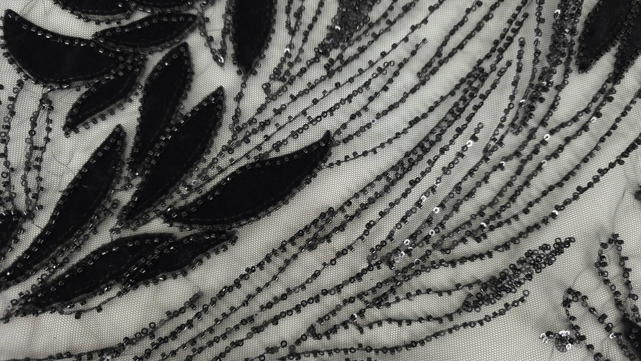 Falduri ale materialului brodat negru cu reflexii discrete de micropaiete