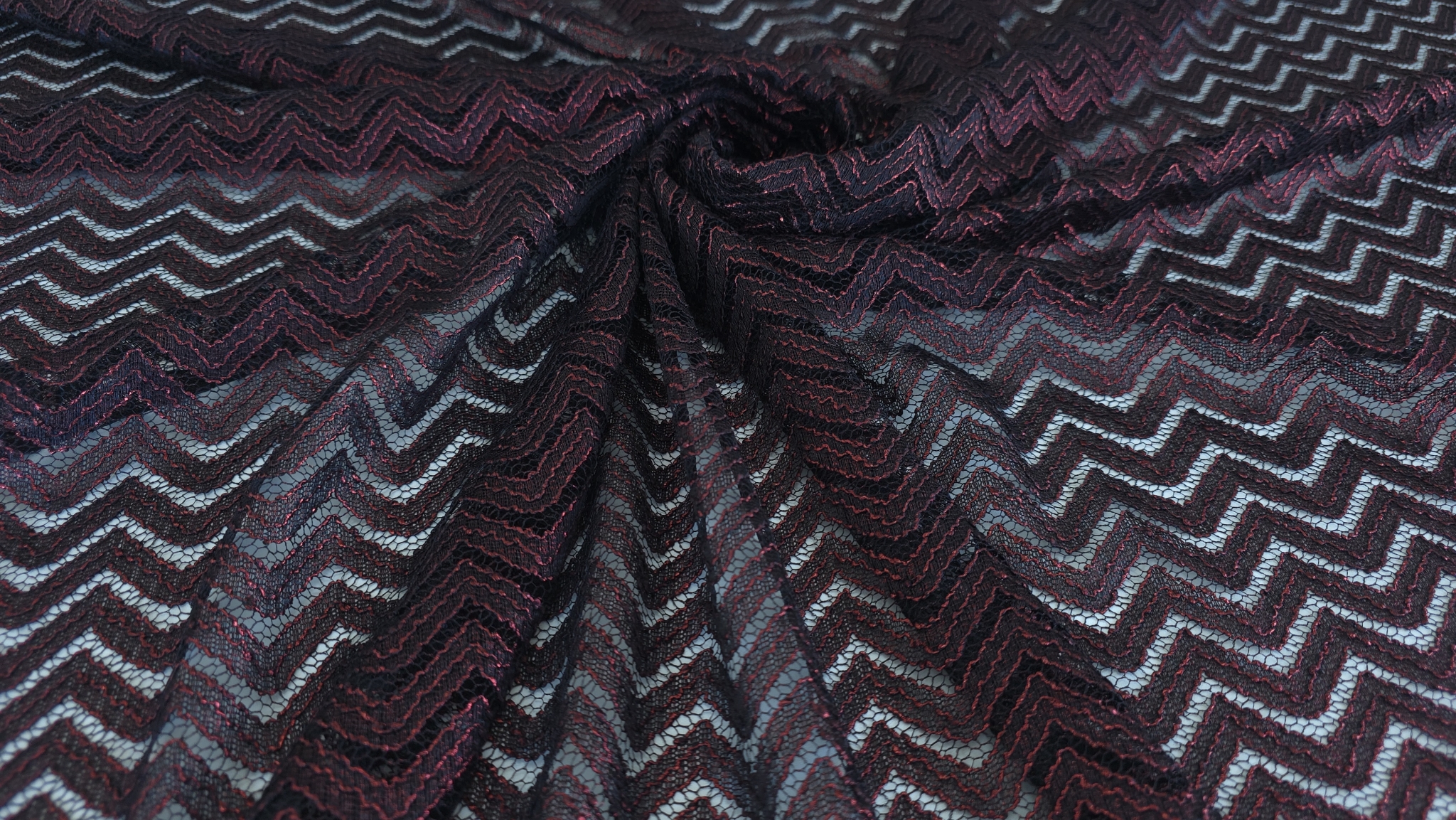 Falduri ale materialului negru cu linii zigzag roșii vizibile în pliuri