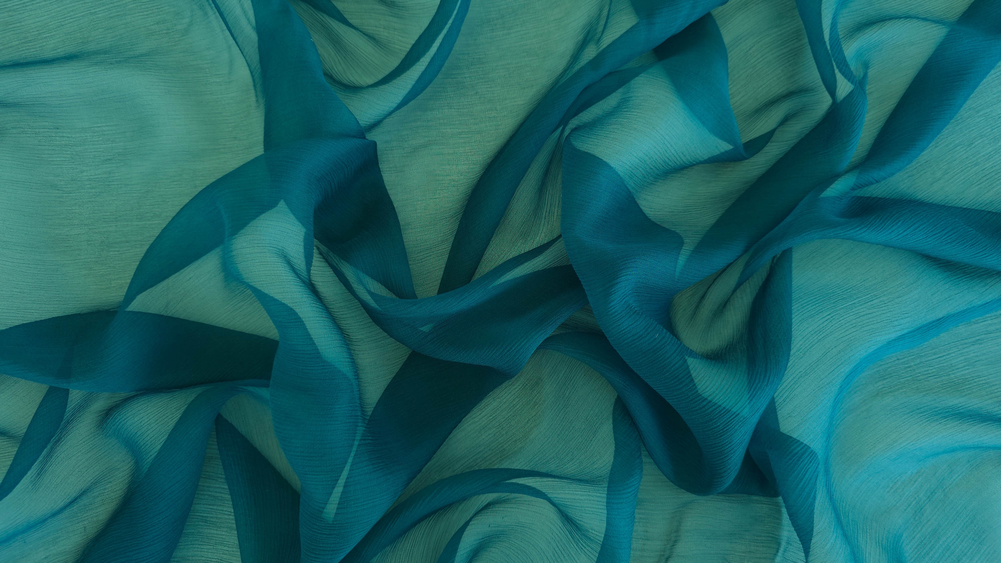 Falduri ample de material albastru petrol creponat cu reflexe verzui în suprapuneri