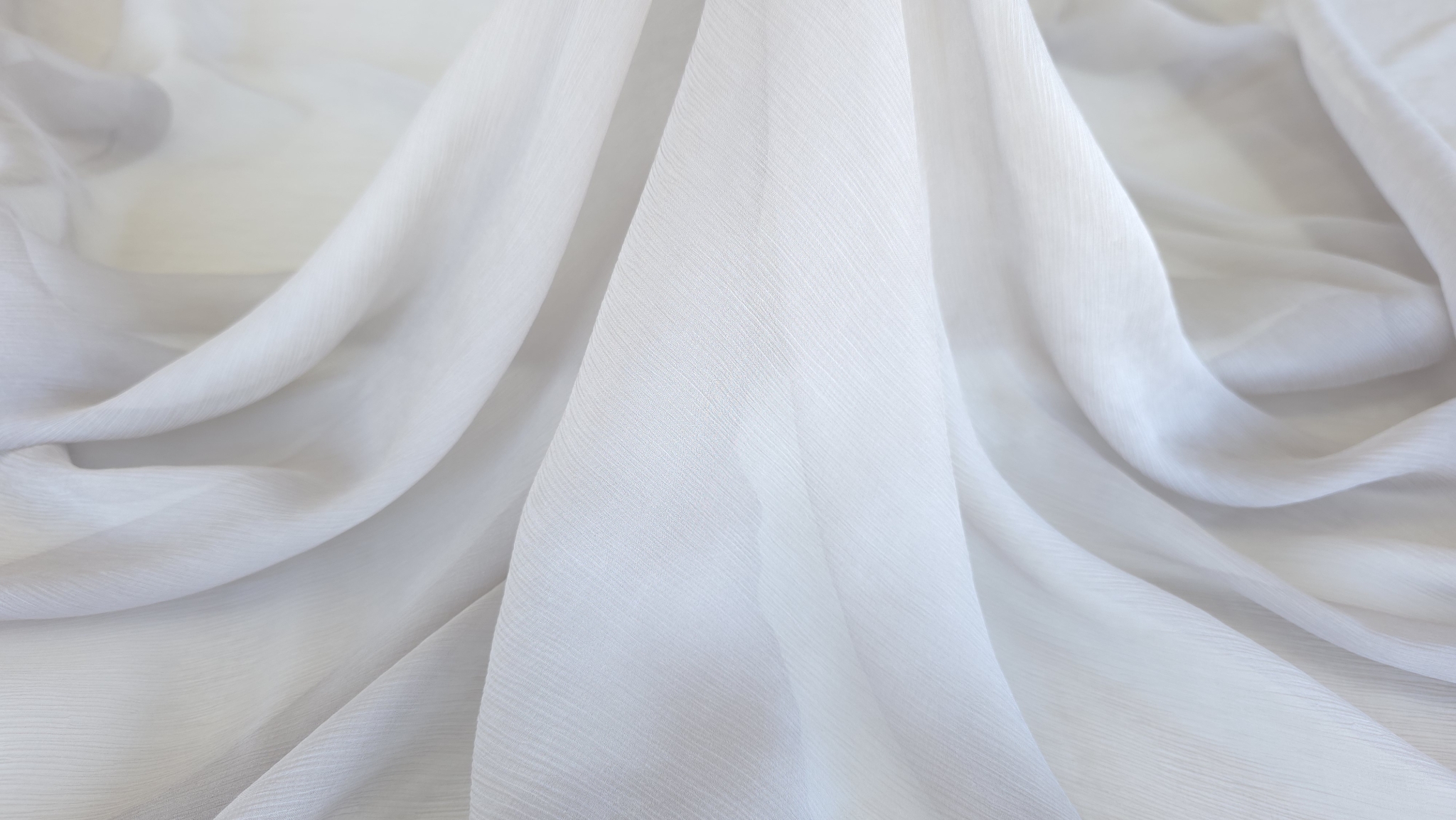 Falduri ample de material creponat în nuanță nisipiu cu joc de lumină și umbră