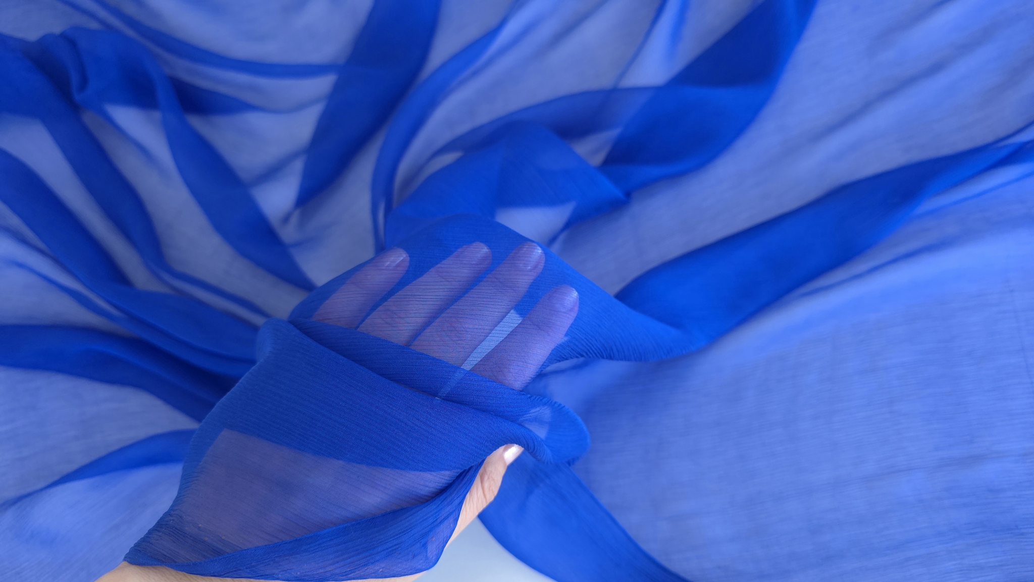 Falduri ample de material transparent albastru intens în plan apropiat