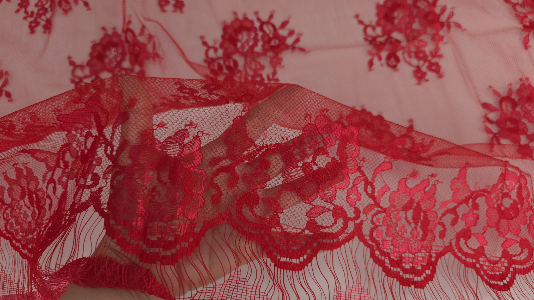 Falduri ridicate ale dantelei roșu Ferrari cu accente metalizate vizibile pe contururile florale