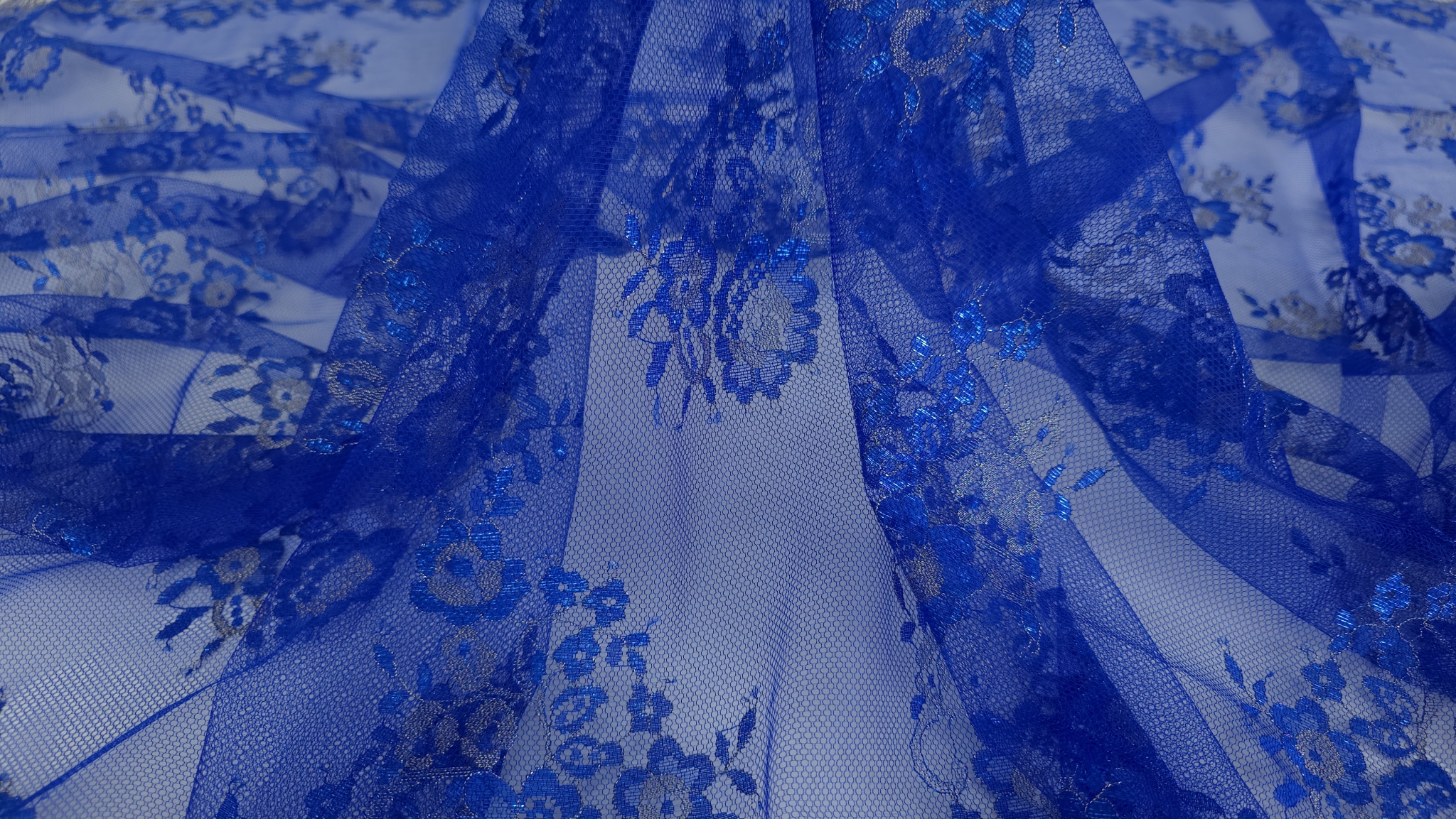 Falduri suprapuse din dantela albastru royal cu inserții argintii și joc de lumină pe straturile de tull