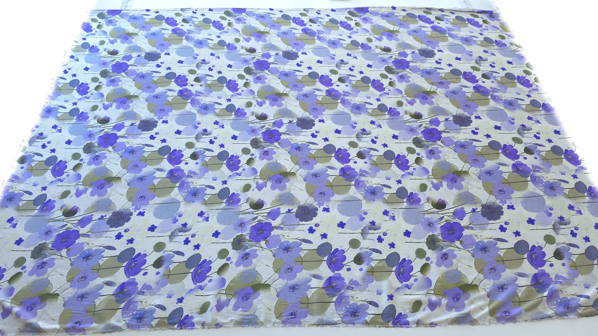 Metraj complet de material floral desfășurat pe masă privit din față