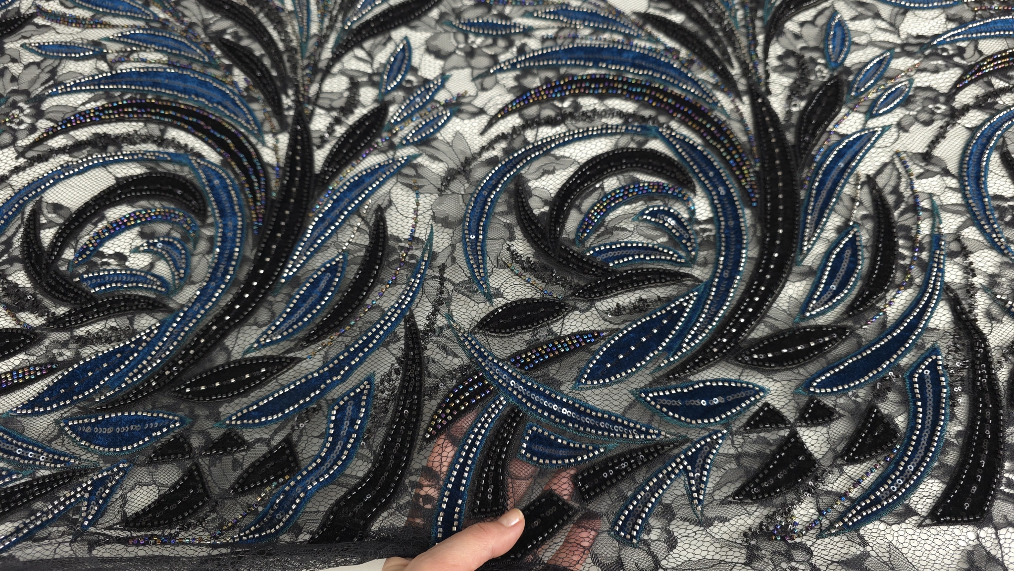 Frunze turcoaz închis alăturate de frunze negre cu margele argintii vizibile