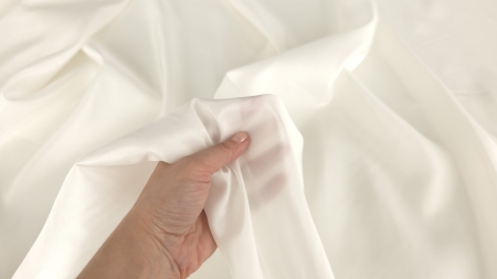 Mână care prezintă transparența căptușelii satinate ivory din mătase 14 momi