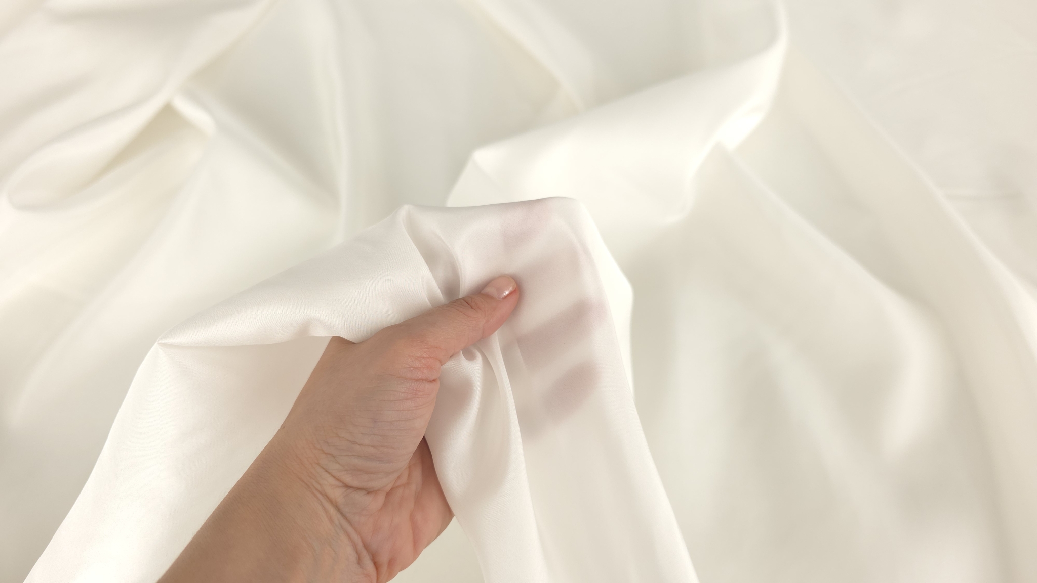 Mână care prezintă transparența căptușelii satinate ivory din mătase 14 momi