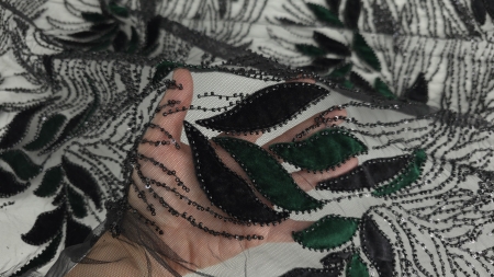 Mână care prezintă transparența tullului cu frunze din catifea neagră și verde pădure