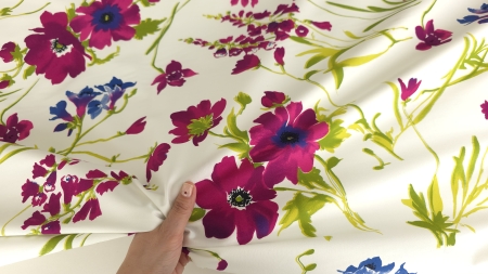 Mână care prinde faldul materialului lângă o floare mare deschisă