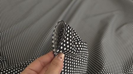 Mână care prinde un fald al materialului cu bulinele aliniate pe pliu