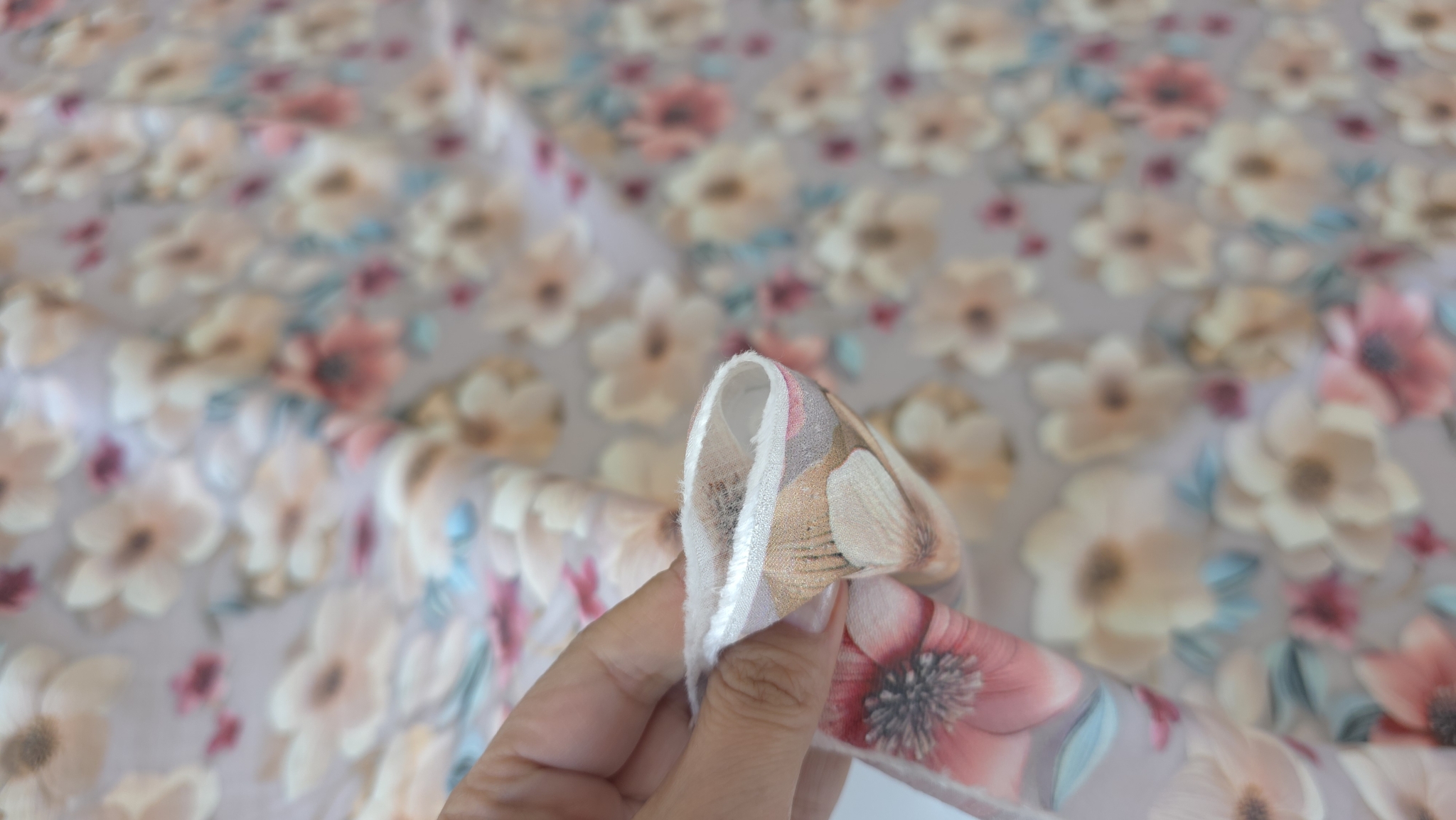 Mână strângând colțul materialului floral sidefat mauve gray cu imprimeu dens în fundal