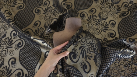 Manechin cu faldul așezat oblic peste bust, cu ornamentul baroc continuând pe fundal