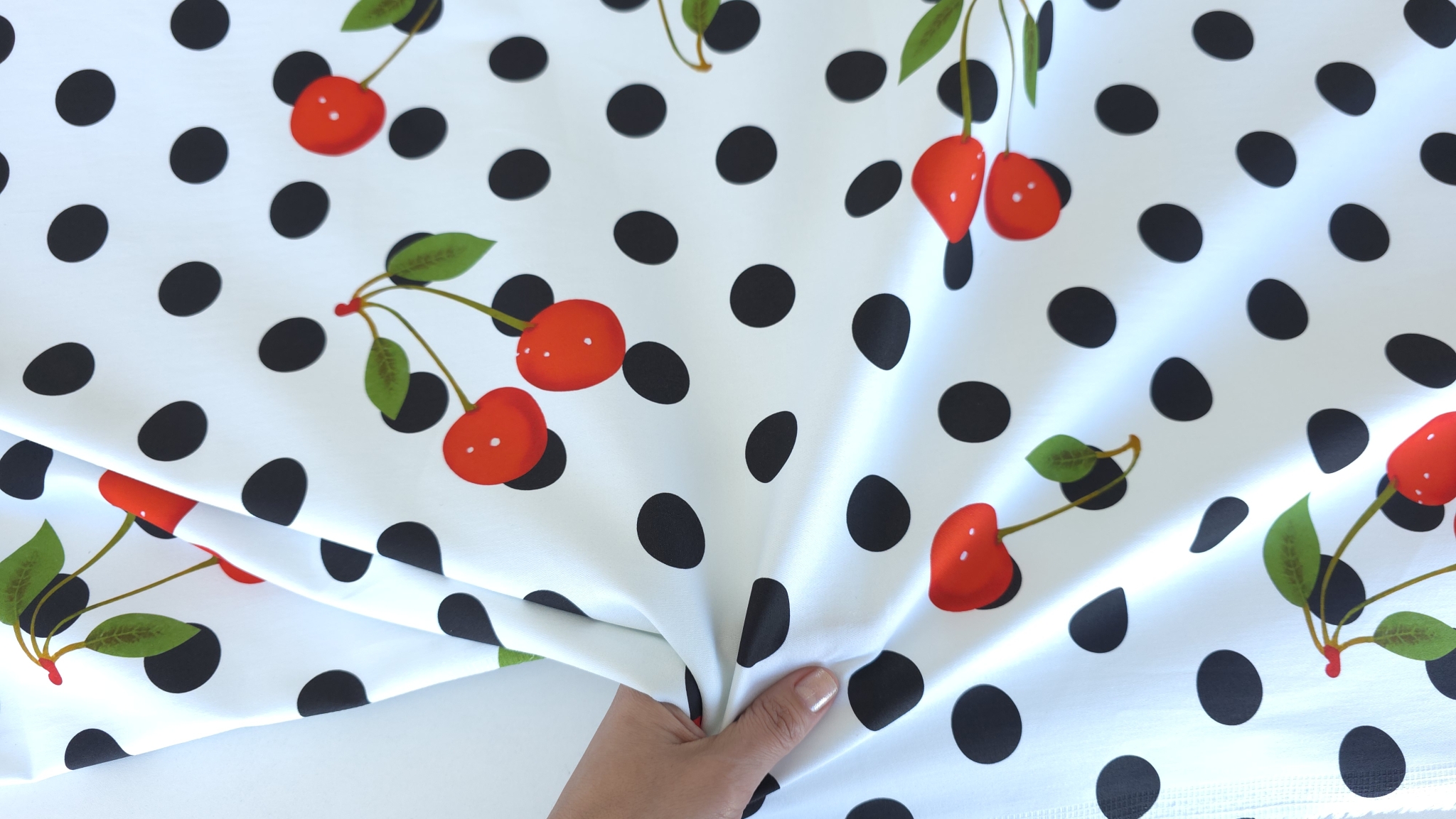 Material denim cherry întins cu buline negre și cireșe distribuite uniform pe suprafața albă