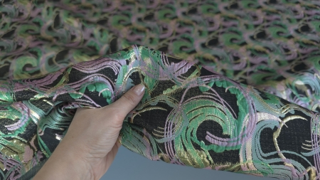 Material dens cu imprimeu verde smarald ținut în mână