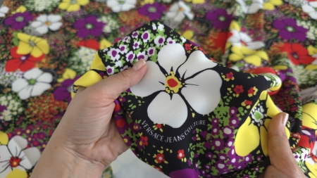 Material jerse elastic cu imprimeu floral, mână trăgând un colț cu floare albă mare