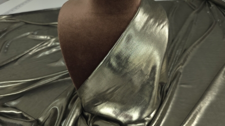 Material metalizat aramă drapat pe manechin, strălucire caldă vizibilă pe bust