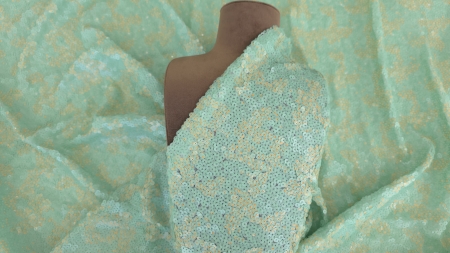 Material mint peach cu micropaiete pe bust maro de prezentare, vedere frontală